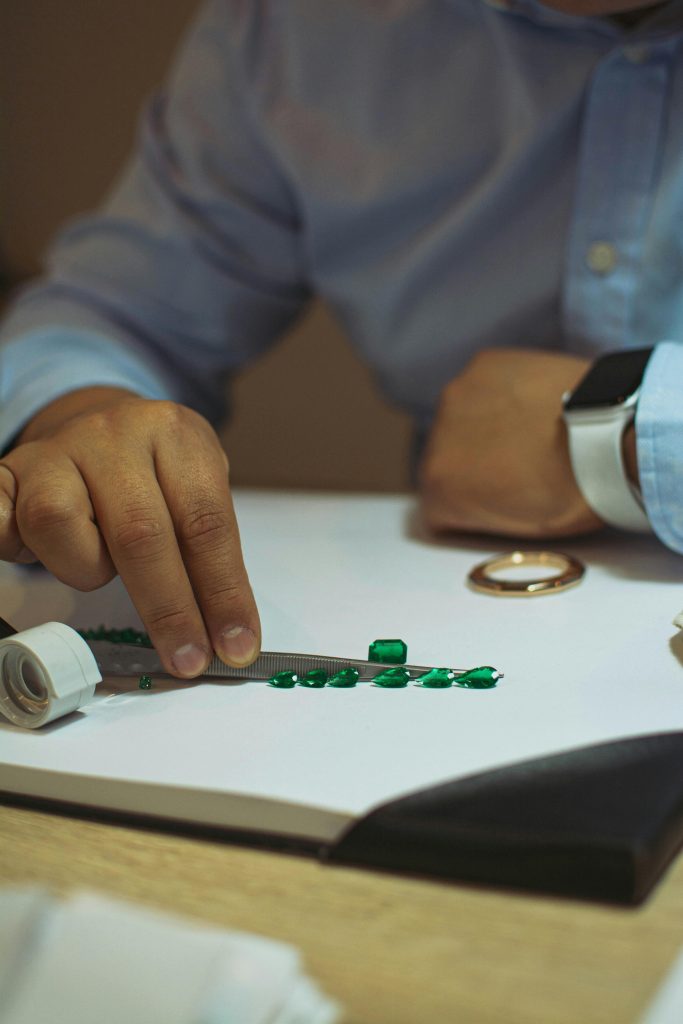 A close-up shot of a man examining emeralds, symbolizing wealth and luxury in a Bogotá jeweler's workshop.